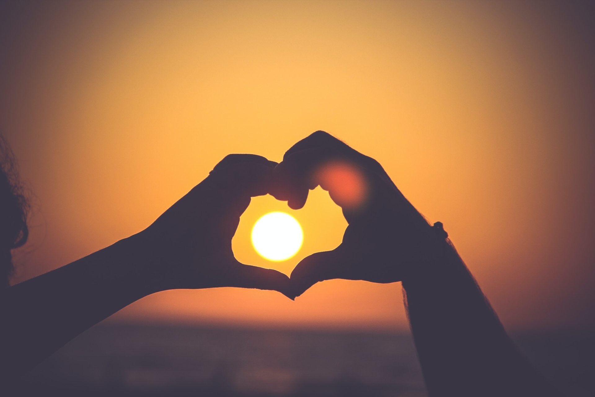 Hands making a heart-shape around the sun