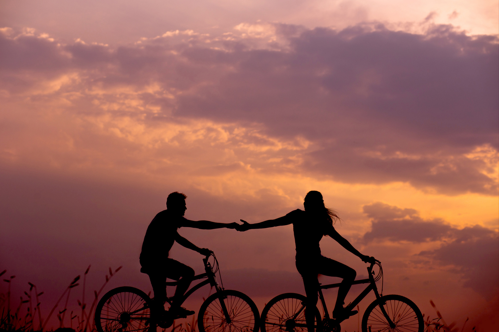 Couple holding hands while riding a bike