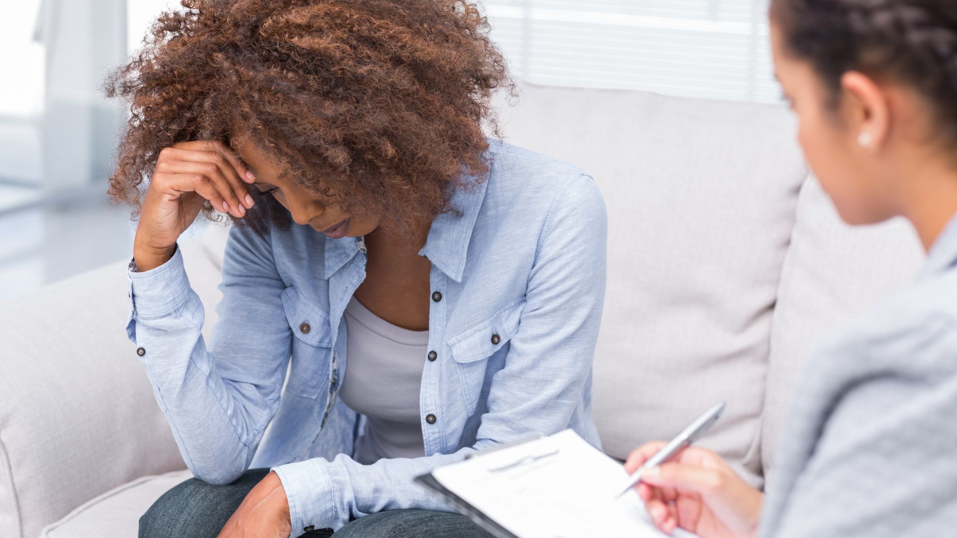 Woman sitting on sofa and crying in therapy