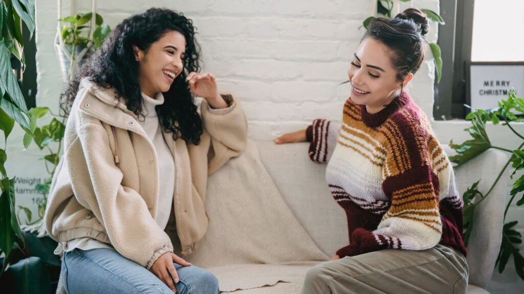 Happy young women sitting on couch and talking